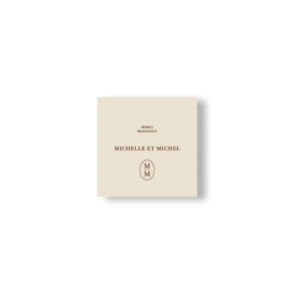 Carte de remerciement carrée crème avec message “Merci beaucoup”, prénoms centrés et monogramme en bas.