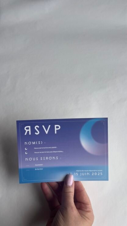 Photo de la carte réponse RSVP de mariage bleu ciel avec un croissant planétaire, zones à remplir pour les noms et nombre d’invités, en typo futuriste blanche.