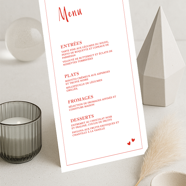 Menu mariage vertical avec titres rouges, texte raffiné en rouge sur fond blanc et deux petits cœurs en bas de carte